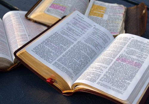 Three open bibles laid out on a table