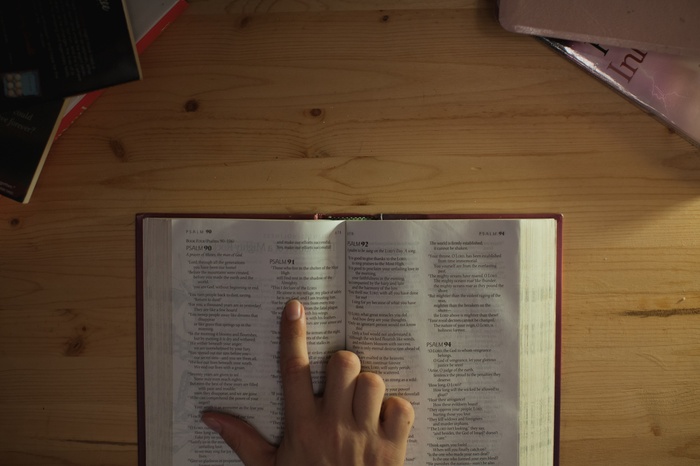 Person pointing to text in an open bible
