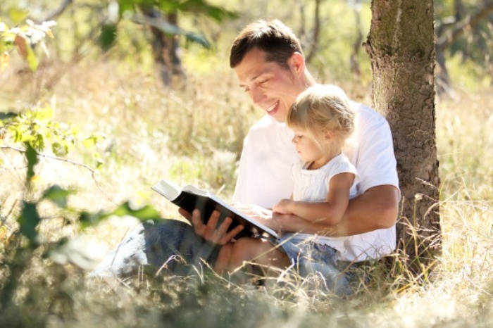 Dad reading to young child outdoors