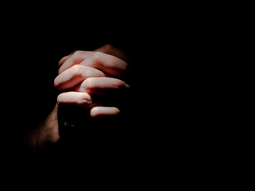 Hands praying in the dark