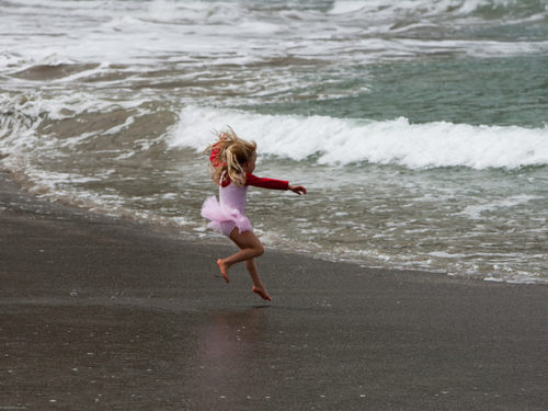 Young girl running into the ocean waves