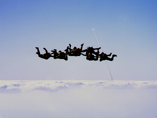 Group of people skydiving and holding hands in midair