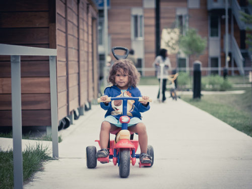 Young child riding a tricycle on a sidewalk
