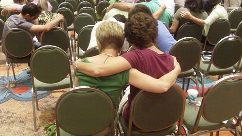 Two people sitting down hugging eachother