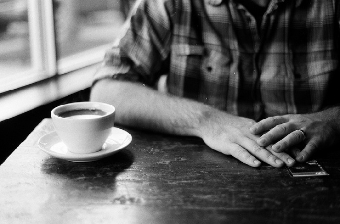 Person sitting at table with a cup of coffee in front of them